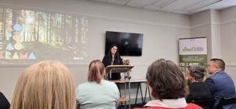A person standing at a podium with a screen on the wall

AI-generated content may be incorrect.
